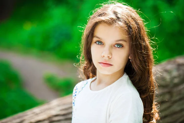 Calm brunette little girl in summer park — ストック写真