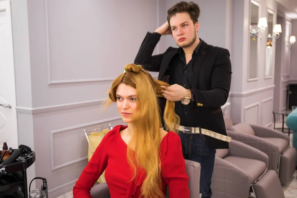 Male hairdresser styling hair for young beautiful woman — ストック写真