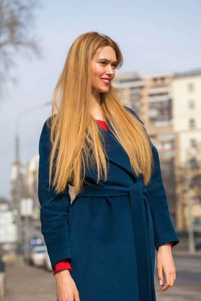 Junge schöne blonde Frau in einem blauen Mantel — Stockfoto