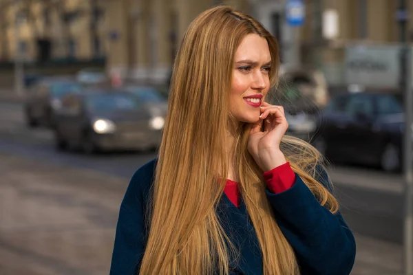 Junge schöne blonde Frau in einem blauen Mantel — Stockfoto