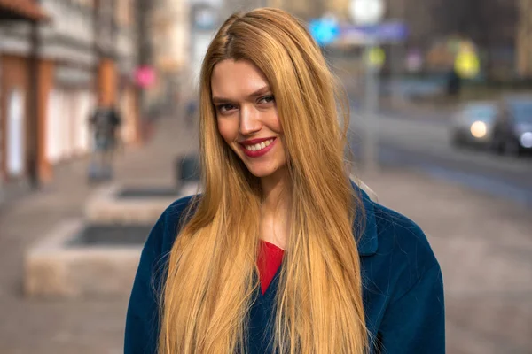 Junge schöne blonde Frau in einem blauen Mantel — Stockfoto