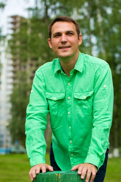 Joven hombre guapo en una camisa verde en el fondo del verano —  Fotos de Stock