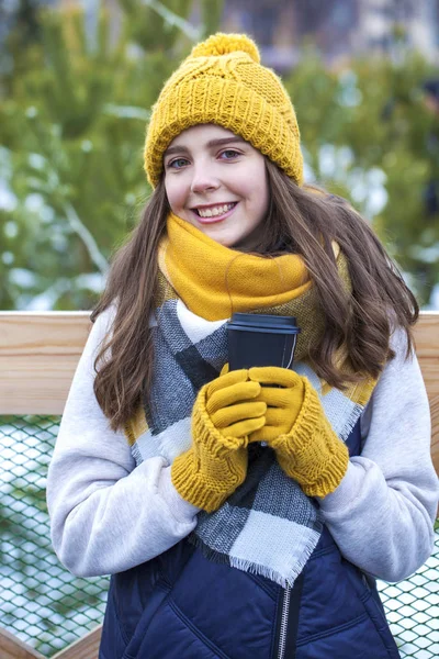 Молодая девушка со стаканом кофе в зимнем парке — стоковое фото