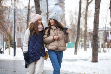 Kış parkında yürüyen iki genç kızın yakın portresi.