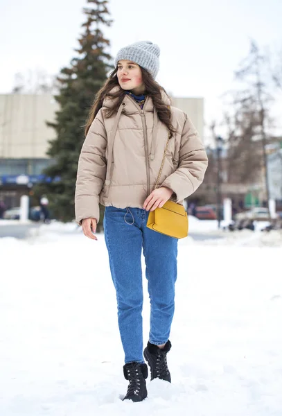 Портрет молодой девушки в синих джинсах, гуляющей в зимнем парке — стоковое фото