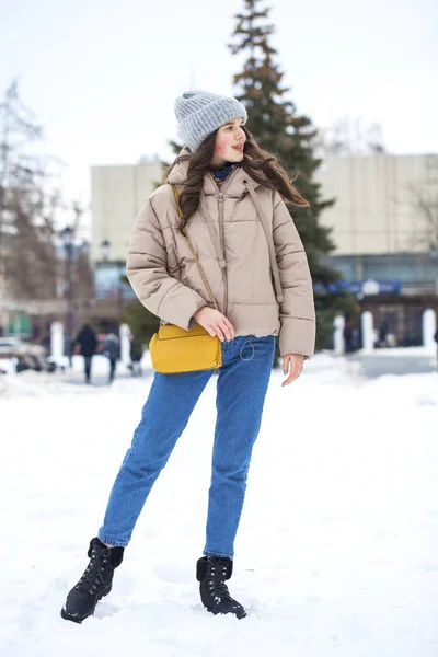 Portrait of young girl in blue jeans walking in a winter park — Stock Photo, Image