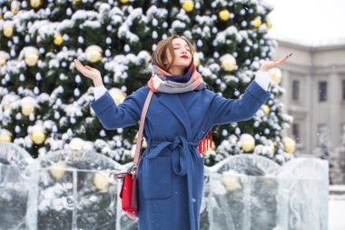 Mavi ceketli mutlu genç kız kış sokağında poz veriyor.