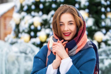 Mavi ceketli mutlu genç kız kış sokağında poz veriyor.