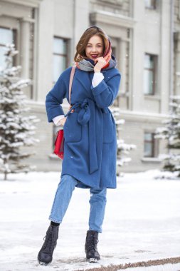 Kışın parkta yürüyen kot pantolonlu genç bir kızın portresi.