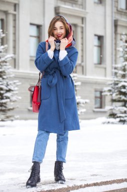 Kışın parkta yürüyen kot pantolonlu genç bir kızın portresi.