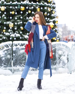 Kışın parkta yürüyen kot pantolonlu genç bir kızın portresi.