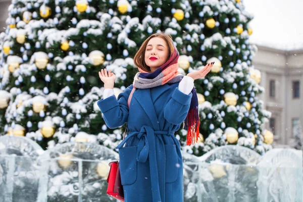Szczęśliwa młoda dziewczyna w niebieskim płaszczu pozowanie w zimowej ulicy — Zdjęcie stockowe