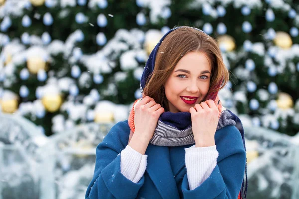 Glückliches junges Mädchen in blauem Mantel posiert in der Winterstraße — Stockfoto