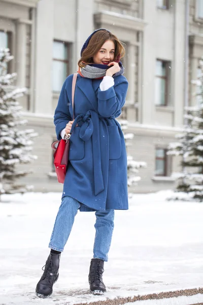 Kışın parkta yürüyen kot pantolonlu genç bir kızın portresi.