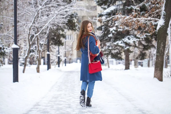 Potret gadis muda dengan celana jeans biru berjalan di taman musim dingin — Stok Foto
