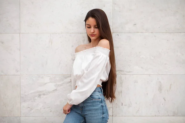 Menina bonita nova em um fundo de uma parede de mármore branco — Fotografia de Stock