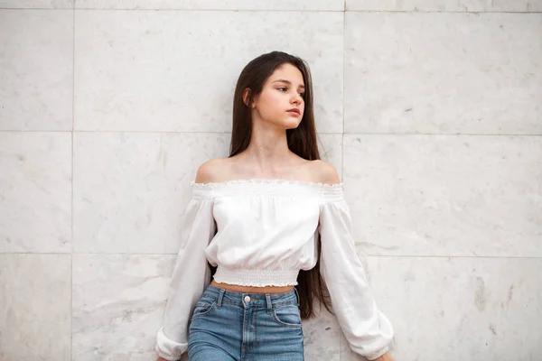 Young beautiful girl on a background of a white marble wall — Stock Photo, Image