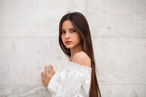 Joven chica hermosa sobre un fondo de una pared de mármol blanco — Foto de Stock