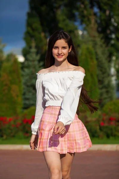 Αρκετά κομψό μελαχρινή κορίτσι με καρό φούστα και λευκή μπλούζα — Φωτογραφία Αρχείου