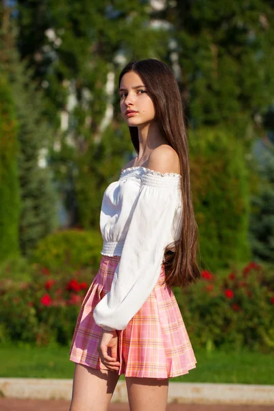 Bella ragazza bruna elegante in gonna a quadri e camicetta bianca — Foto Stock