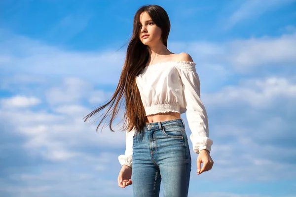 Young beautiful brunette woman in jeans and white blouse walking — Stock Photo, Image