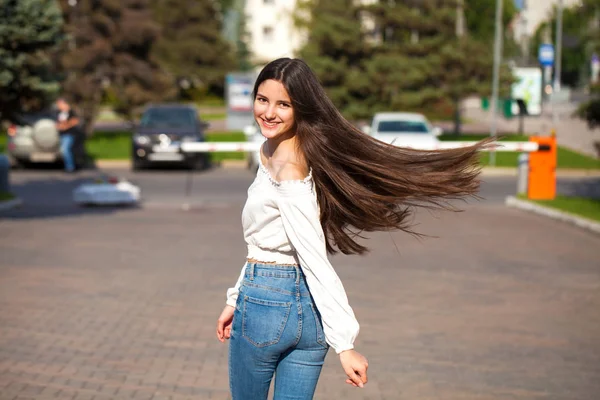 Jovem bela mulher morena em jeans e blusa branca andando — Fotografia de Stock