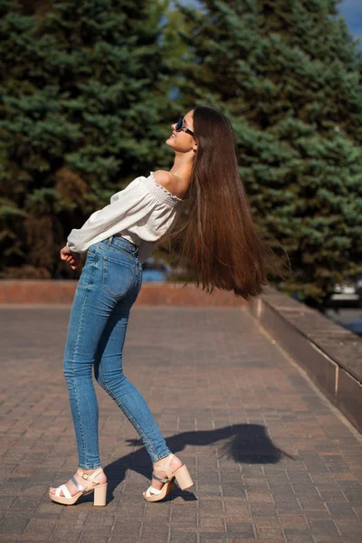 Bella ragazza bruna elegante in jeans blu e camicetta bianca — Foto Stock