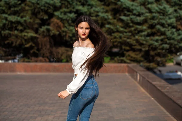 Jovem bela mulher morena em jeans e blusa branca andando — Fotografia de Stock