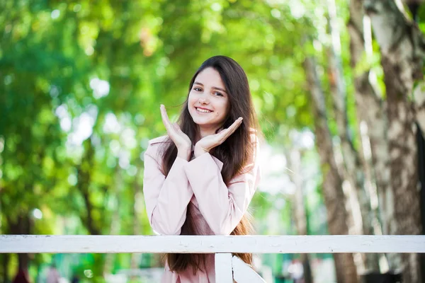 Portrait of a young brunette girl in pink coat on a background o — Stock Photo, Image
