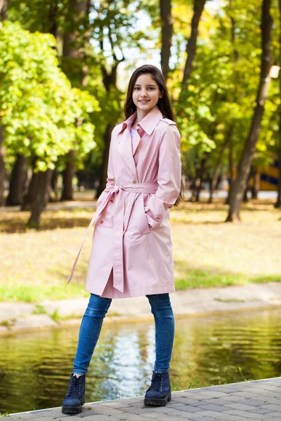 Retrato de una joven morena con abrigo rosa sobre un fondo o —  Fotos de Stock