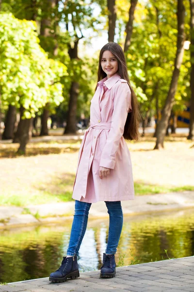 Portré egy fiatal barna lány rózsaszín kabát a háttérben o — Stock Fotó