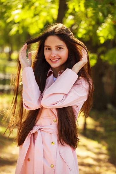 Portret młodej dziewczyny Brunetki w różowym płaszczu na tle o — Zdjęcie stockowe
