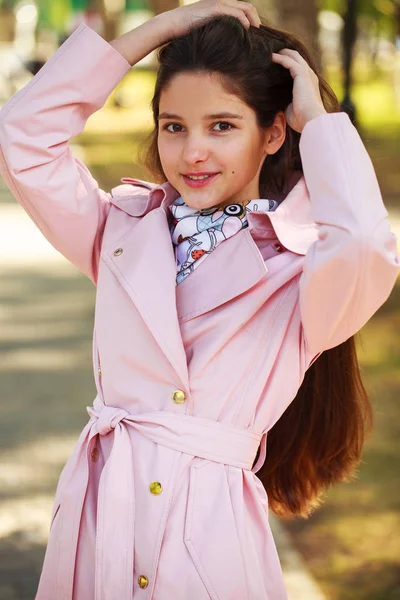 Porträt eines jungen brünetten Mädchens in rosa Mantel auf einem Hintergrund o — Stockfoto