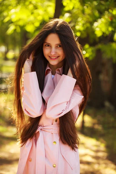 Ritratto di una giovane ragazza bruna in cappotto rosa su sfondo o — Foto Stock