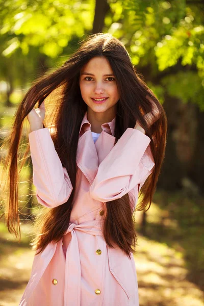 Портрет молодой брюнетки в розовом пальто на заднем плане — стоковое фото