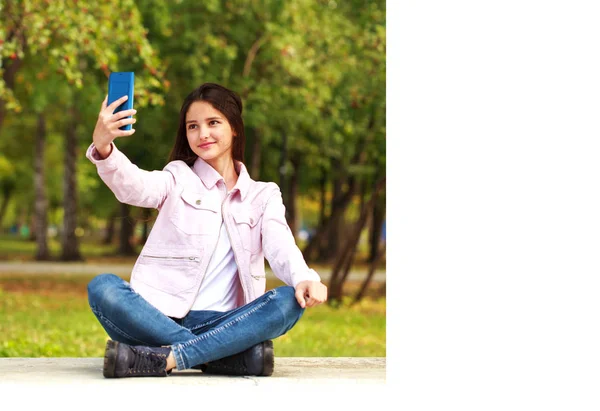 Μελαχρινή κορίτσι φωτογραφίες τον εαυτό της σε ένα κινητό τηλέφωνο ενώ κάθεται — Φωτογραφία Αρχείου