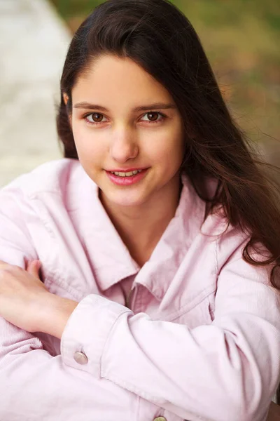 Retrato de uma jovem morena de casaco rosa em um fundo o — Fotografia de Stock