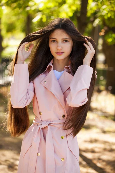 Retrato de una joven morena con abrigo rosa sobre un fondo o — Foto de Stock