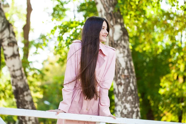 Ritratto di una giovane ragazza bruna in cappotto rosa su sfondo o — Foto Stock