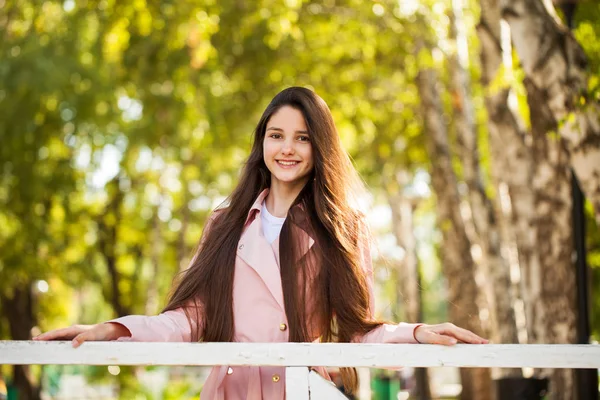 Porträt eines jungen brünetten Mädchens in rosa Mantel auf einem Hintergrund o — Stockfoto