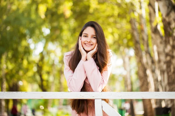 Portret van een jong brunette meisje in roze vacht op een achtergrond o — Stockfoto