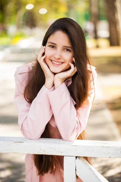 Ritratto di una giovane ragazza bruna in cappotto rosa su sfondo o — Foto Stock