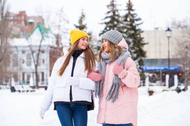 İki mutlu güzel kız arkadaş kışın şehir merkezinde yürür.