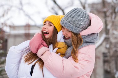 İki mutlu güzel kız arkadaş kışın şehir merkezinde yürür.