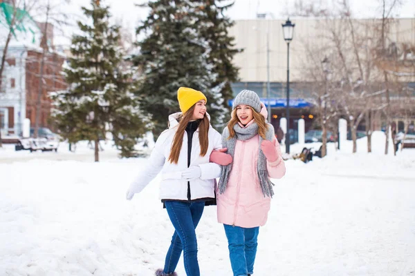 Twee gelukkige mooie vriendinnen wandelen in de winter in een stad par — Stockfoto