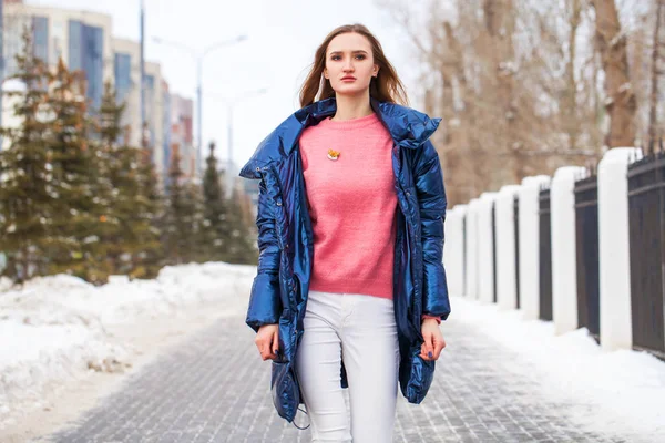 Young blonde woman in blue down jacket in winter street — 스톡 사진