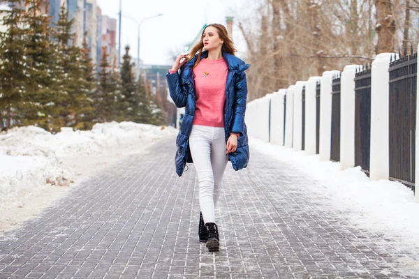 Young blonde woman in blue down jacket in winter street — 스톡 사진