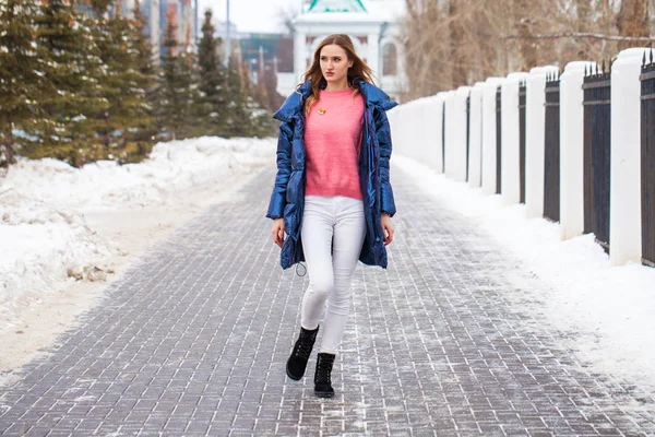 Jonge blonde vrouw in blauw donsjas in de winter straat — Stockfoto