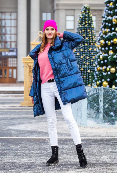 Junge blonde Frau in blauer Daunenjacke in der Winterstraße — Stockfoto
