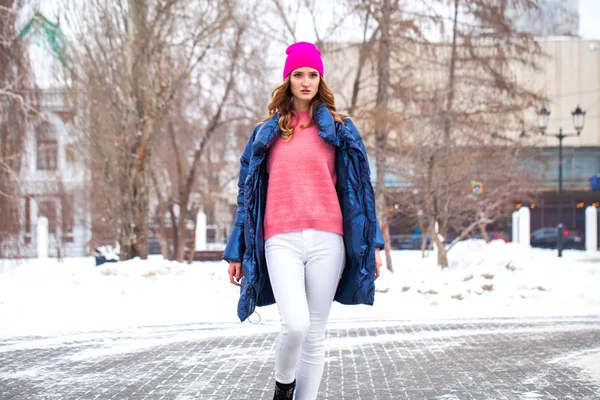 Jonge blonde vrouw in blauw donsjas in de winter straat — Stockfoto